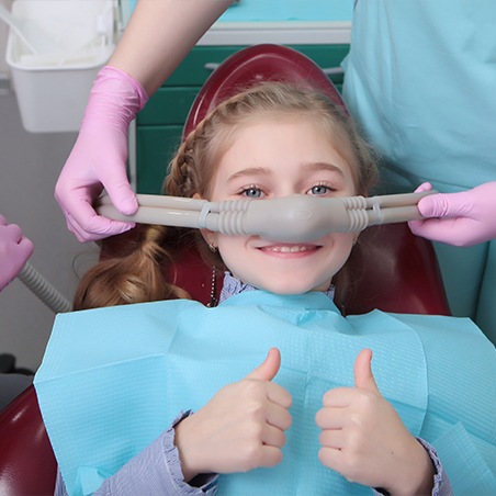 Dentist placing nitrous oxide sedation dentistry mask on child's nose