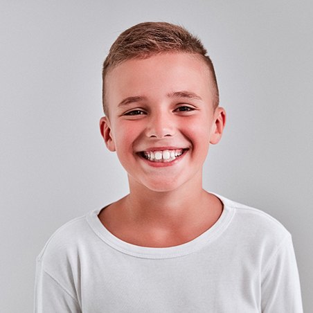 Happy boy in white shirt, enjoying benefits of tooth-colored fillings